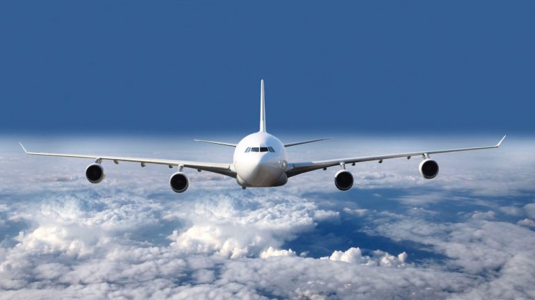 All white plane in the air in the clouds