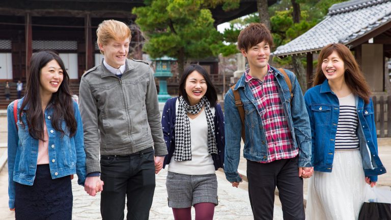 Young japanese students visiting temple with friends in kyoto japan